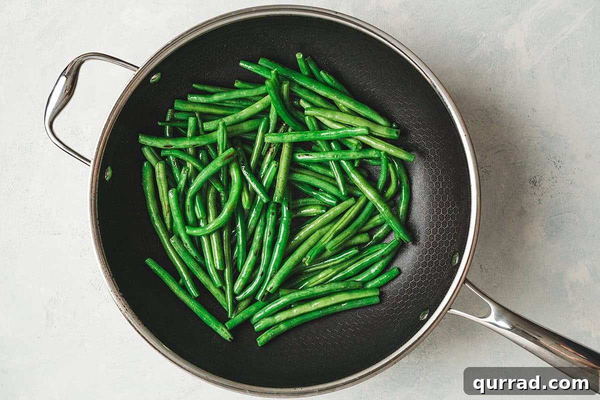 Garlic Green Beans Recipe: Sautéed with Lemon and Butter 5 Green beans cooking in a skillet.