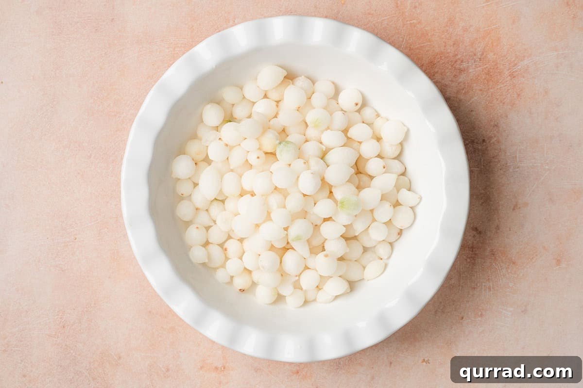 One-Pot Mini Pearl Onion Boil with Garlic and Herbs 5 Pearl onions in a pie dish.