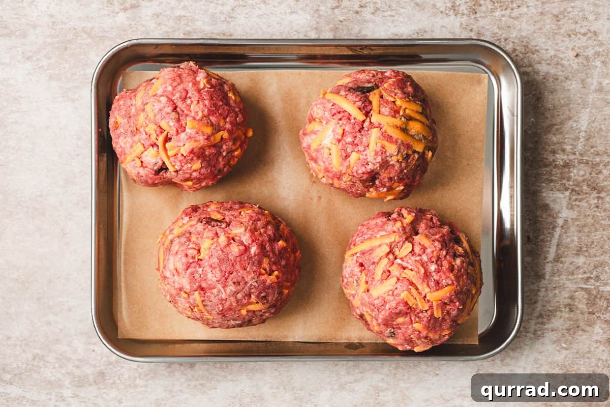 Four meatballs for crack smash burgers on a baking sheet.