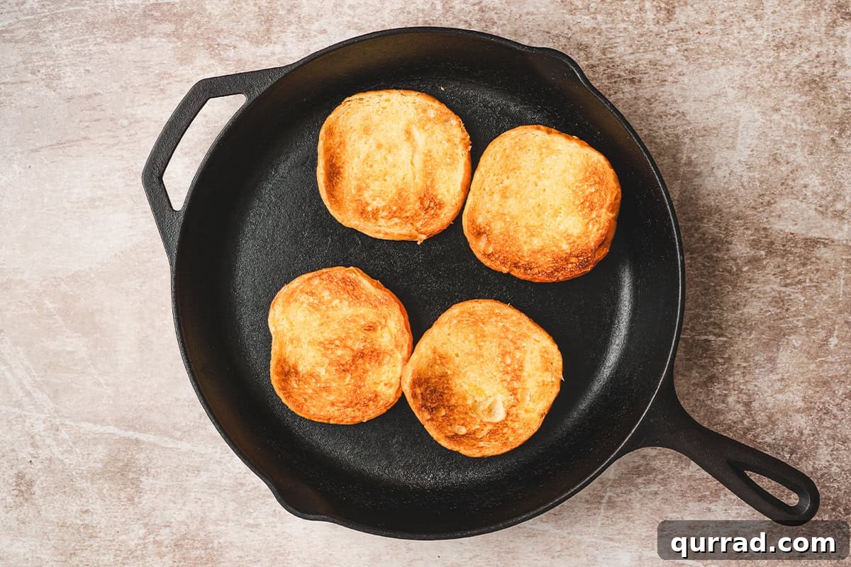 Hamburger buns toasting in a skillet.