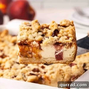 Irresistible Peach Cobbler Cheesecake Bars 3 Side view of a peach cobbler cheesecake bar being lifted out of a baking dish.