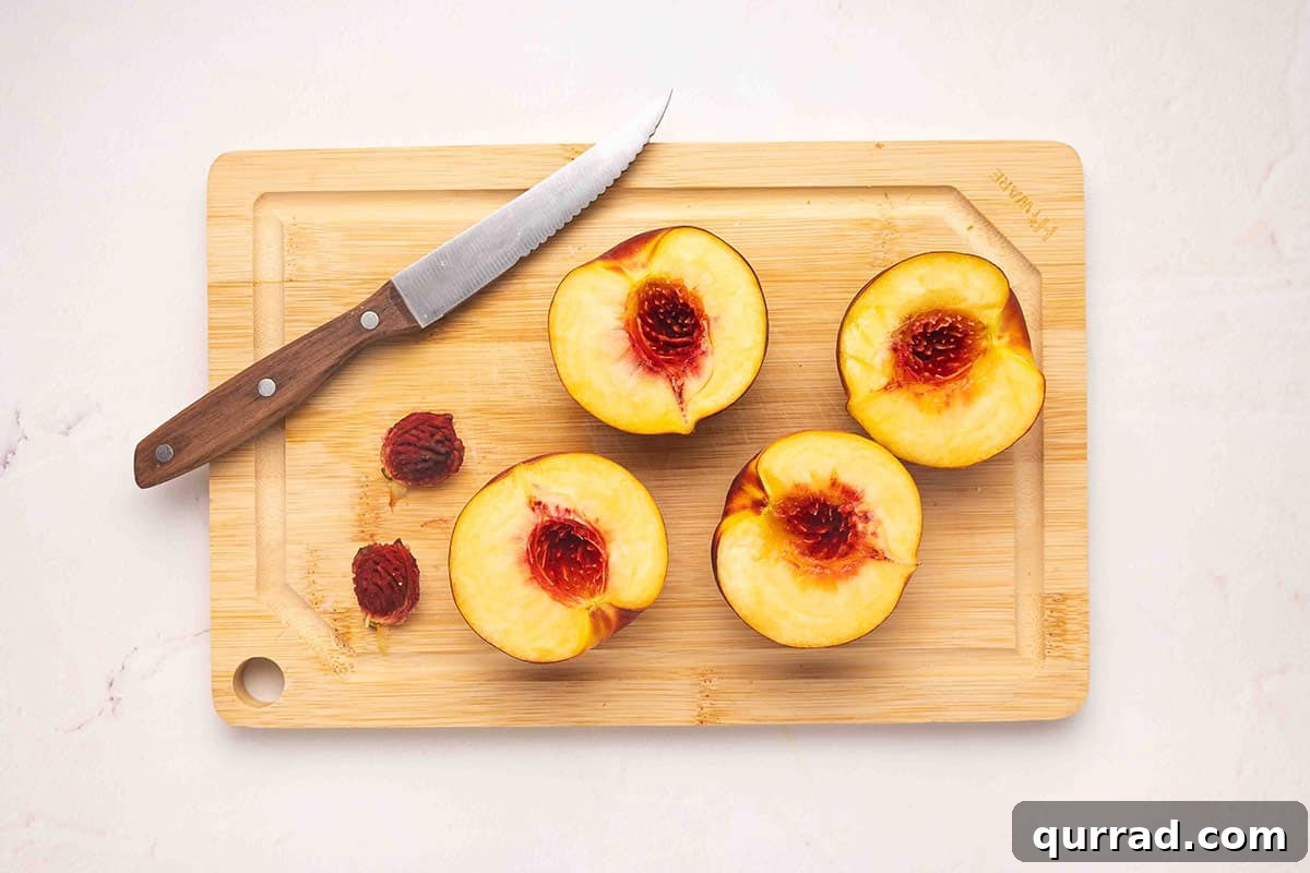 Air Fryer Peaches with Honey and Cinnamon 5 Peaches sliced in half on a cutting board with the pits removed.