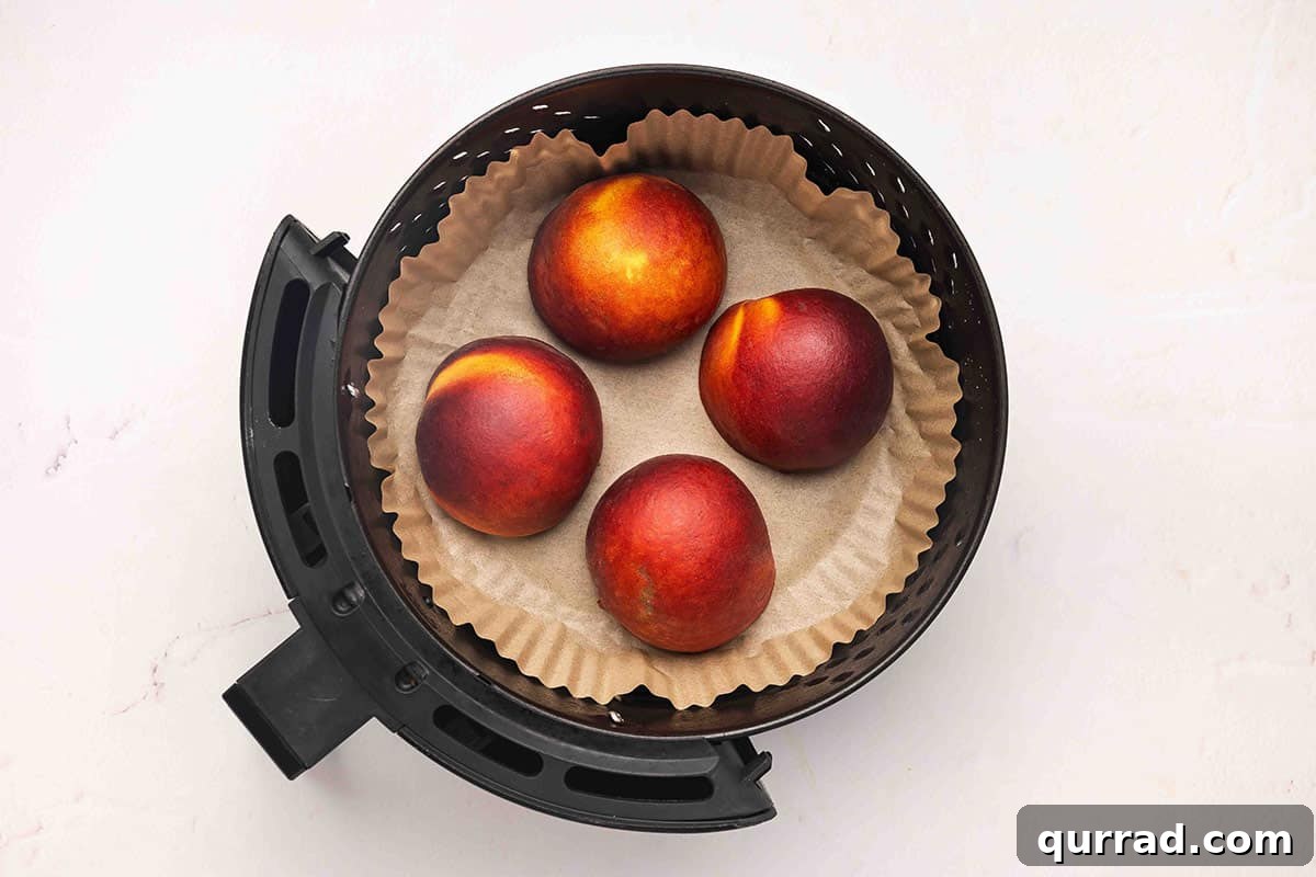 Air Fryer Peaches with Honey and Cinnamon 6 Peach halves in an air fryer basket.