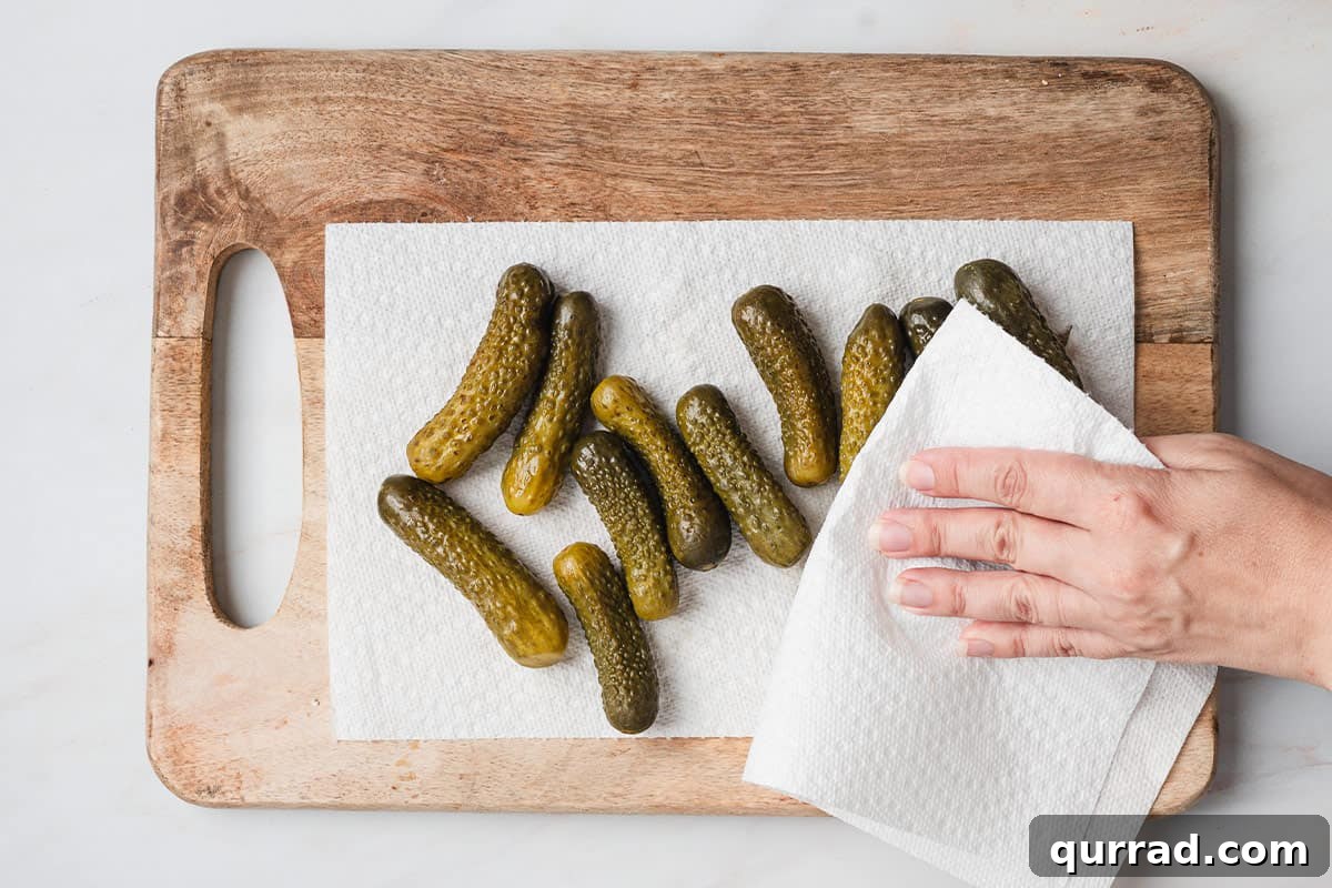 Mini Pickle and Salami Taco Bites 5 A hand drying mini pickles with paper towels.