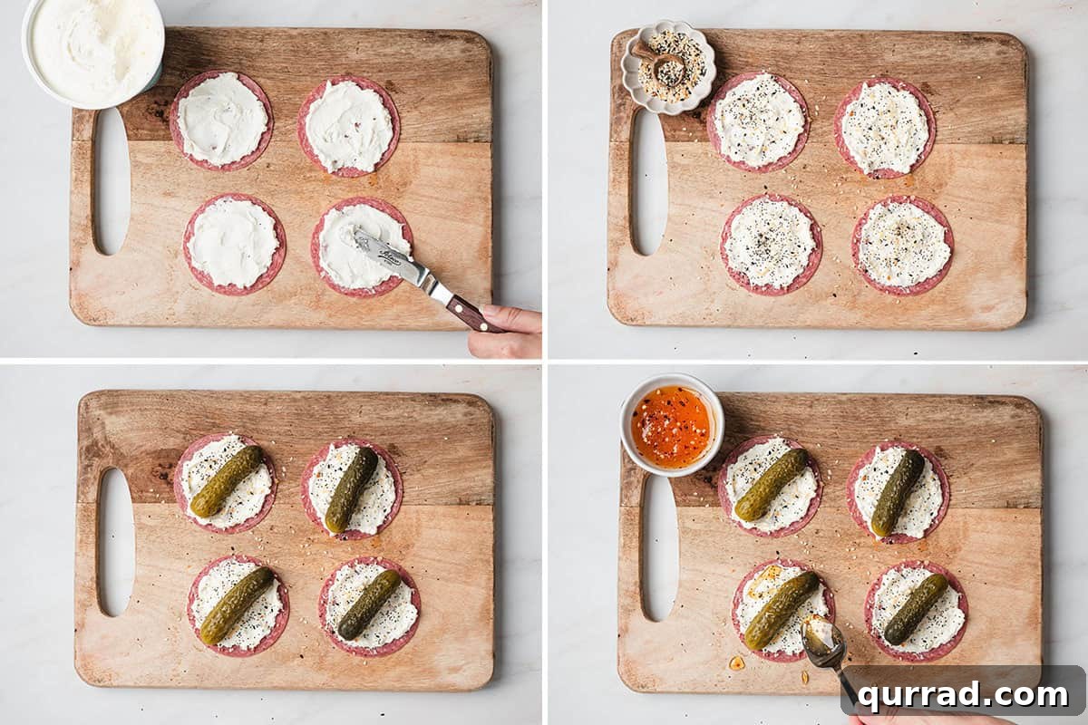 Mini Pickle and Salami Taco Bites 6 Whipped cream cheese being spread on salami, followed by everything bagel seasoning added, followed by a mini pickle added to the center of the salami, then a spoon drizzling hot honey over the pickle tacos.