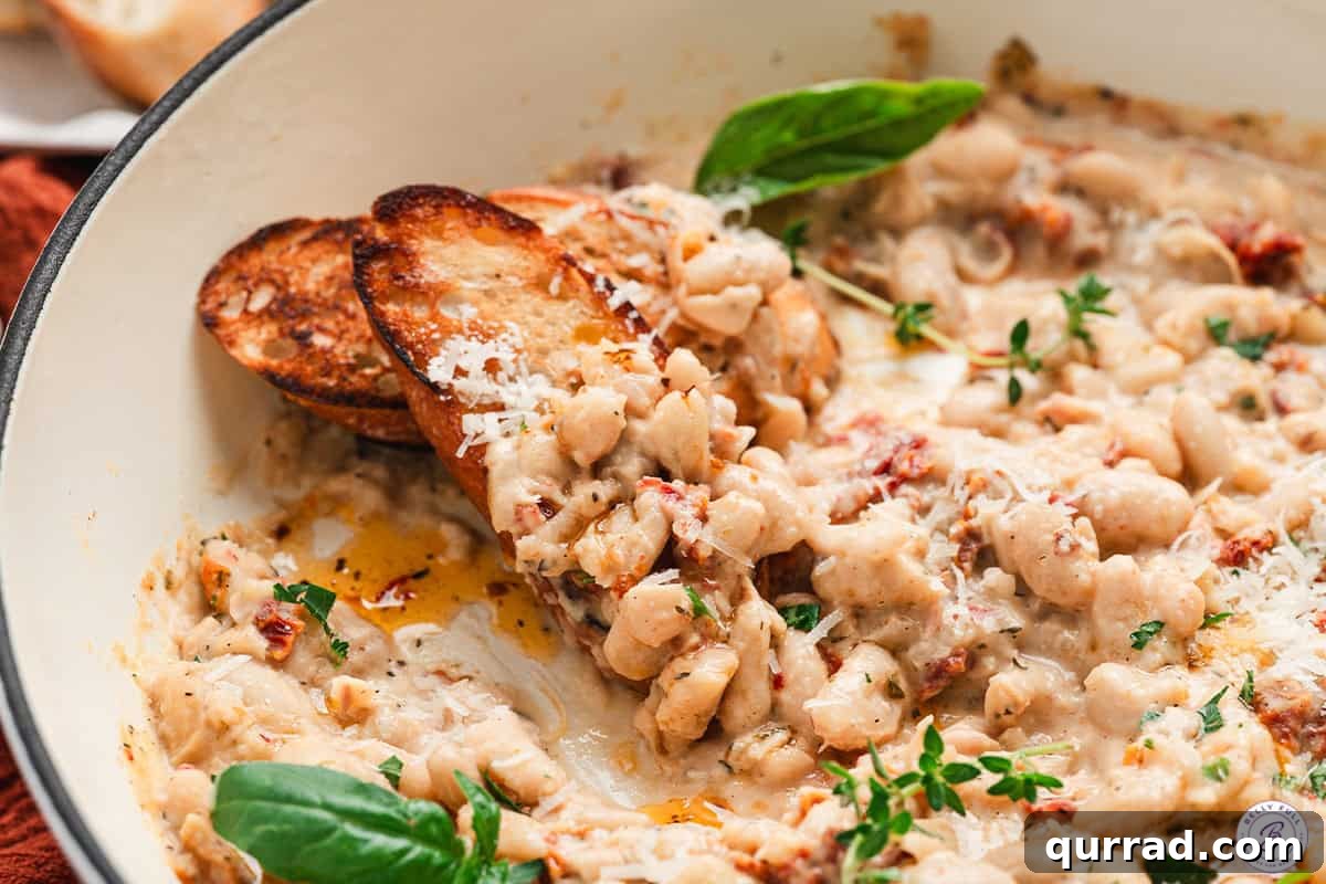 Marry Me Beans: Creamy Tomato and Herb Skillet 11 Side view of Marry Me beans in a skillet with slices of crusty bread.