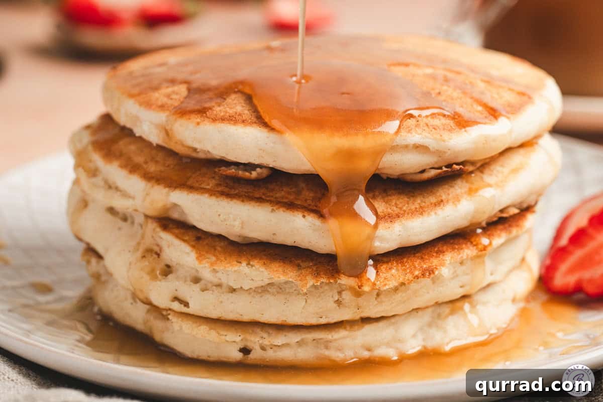 Side view of a stack of pancakes topped with maple butter syrup.