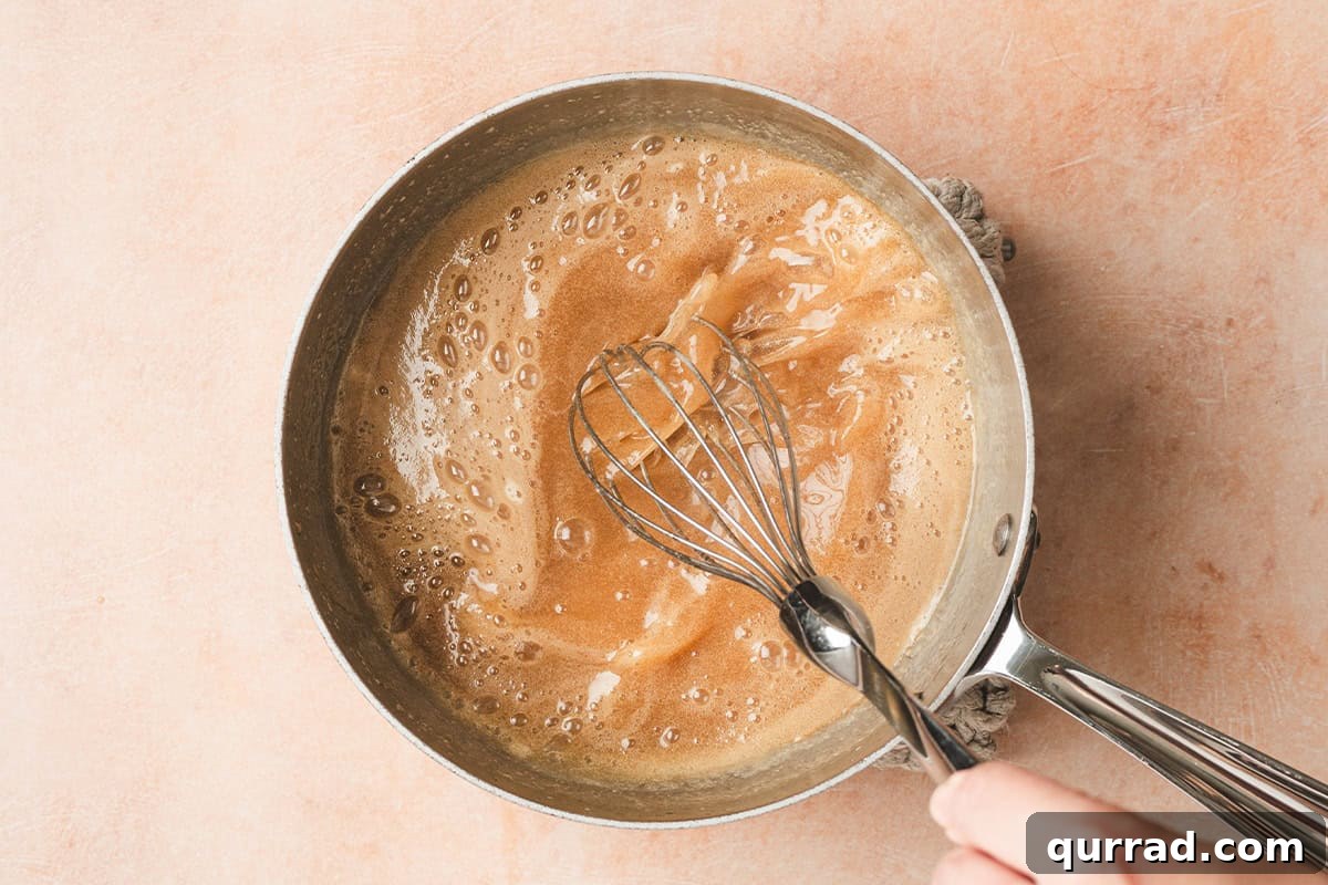 Foaming maple butter syrup in a sauce pan being whisked.
