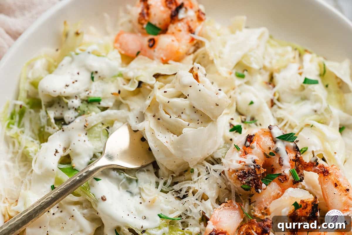 Creamy Alfredo Cabbage Ribbons 10 Overhead close up of alfredo cabbage ribbons on a fork with shrimp.