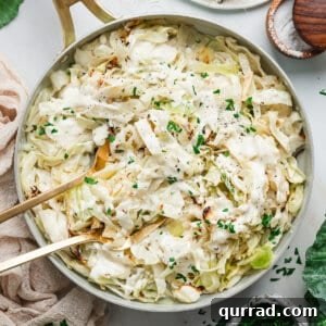 Creamy Alfredo Cabbage Ribbons 3 Overhead view of a skillet with alfredo cabbage ribbons with kitchen tongs.