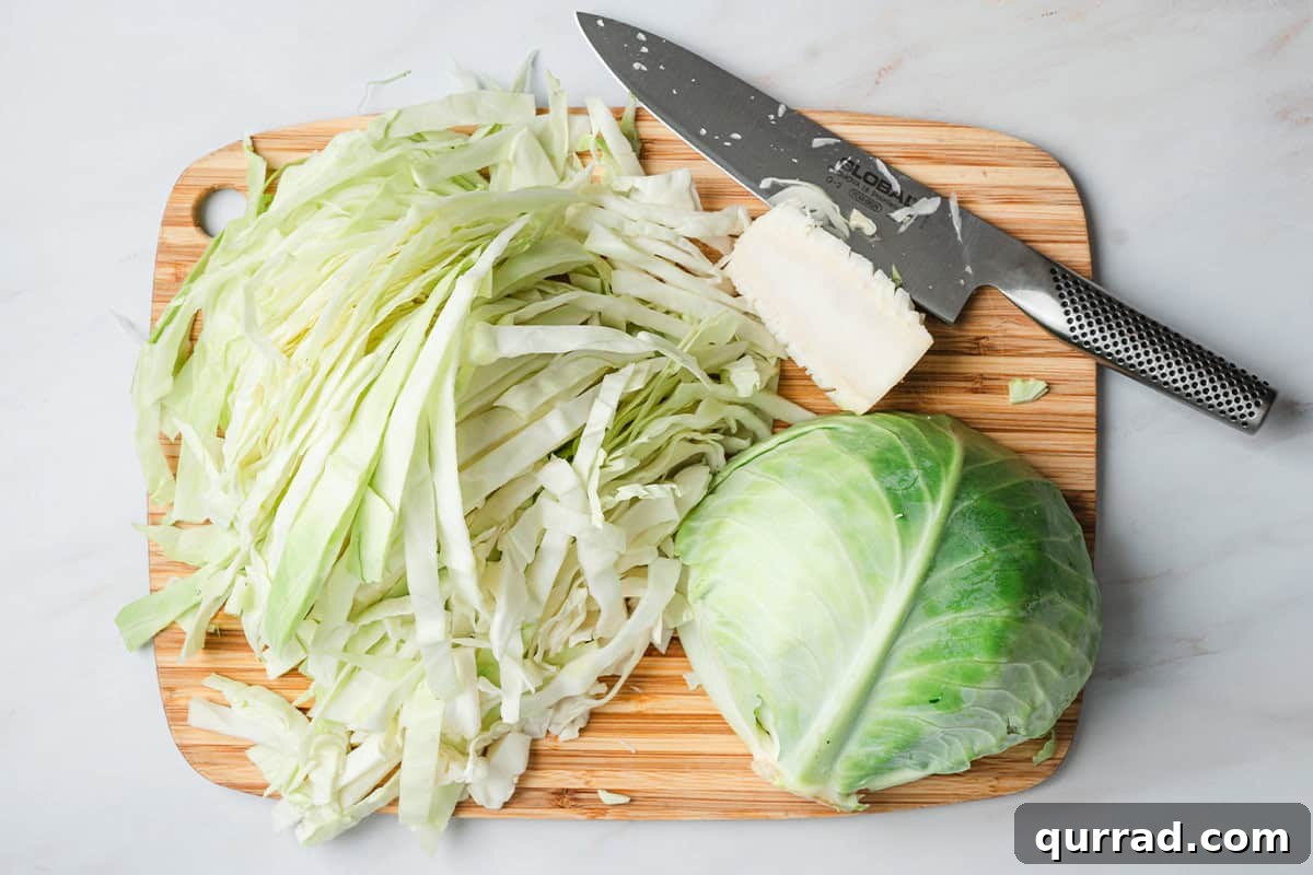 Creamy Alfredo Cabbage Ribbons 5 A cabbage on a cutting board with half cut into thin ribbons.